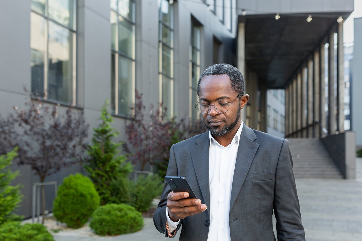 businessman looking at phone by voronaman via shutterstock