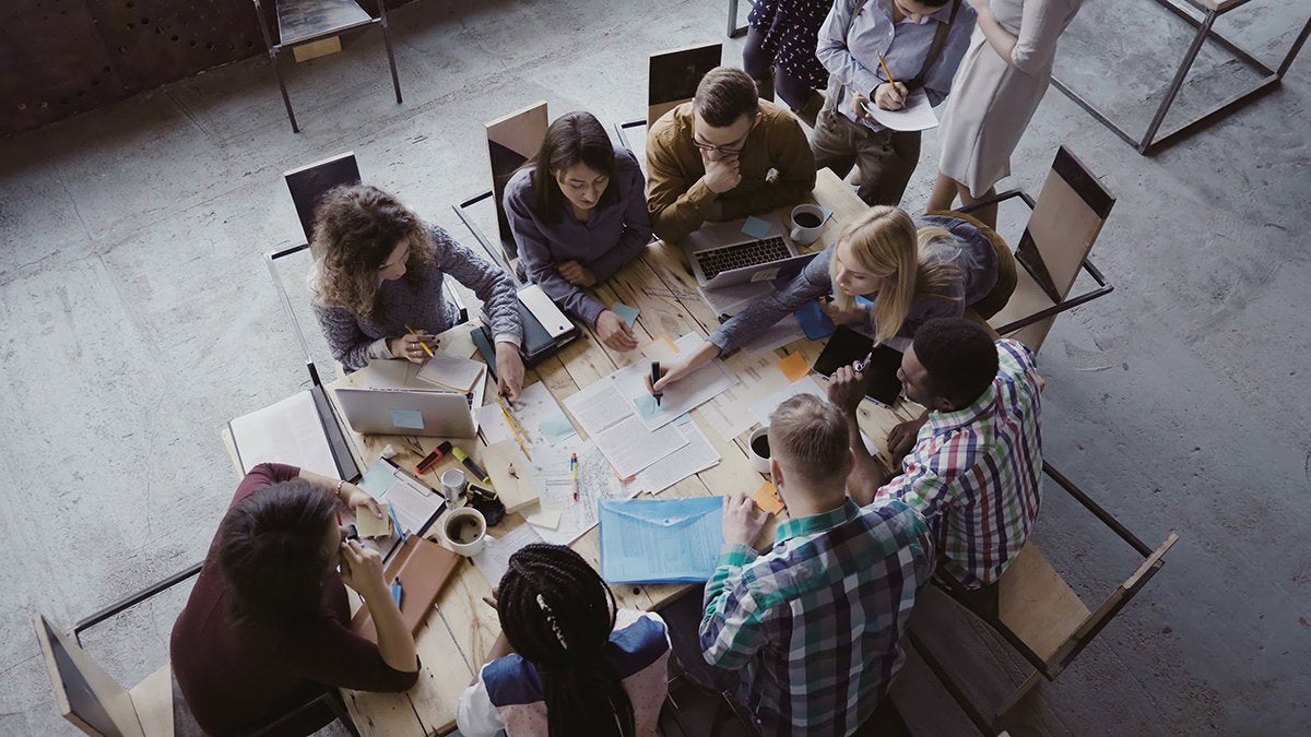 a team gathers around a table to work