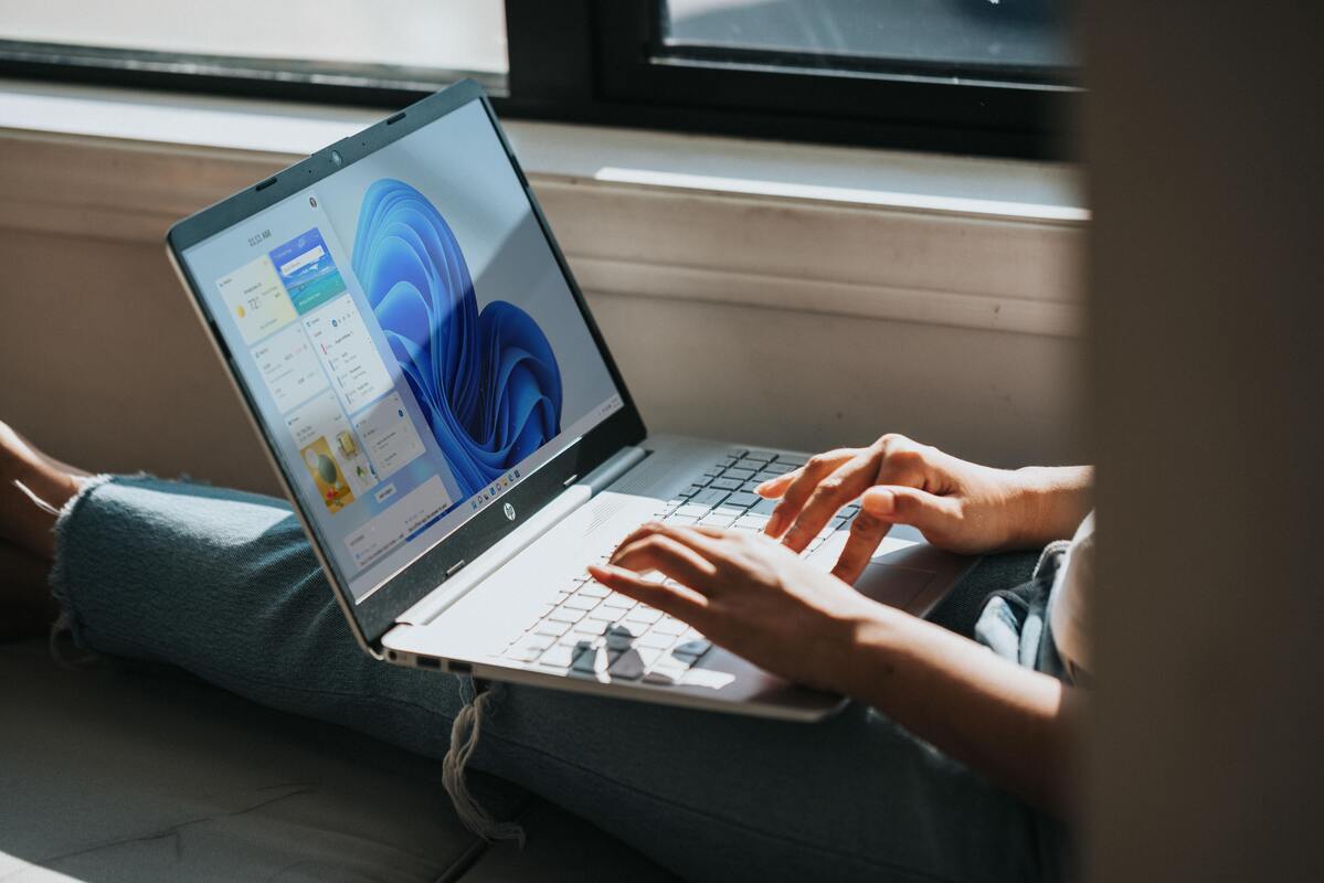 Person using Windows 11 on a laptop next to a sunny window